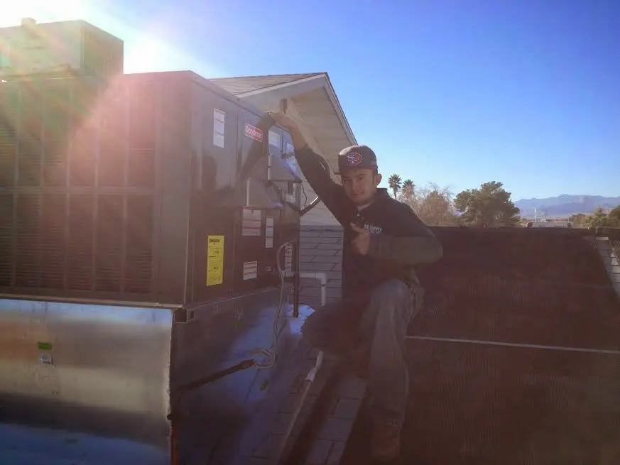 HVAC technician performing AC Tune-Up on a rooftop unit in Ocean Springs