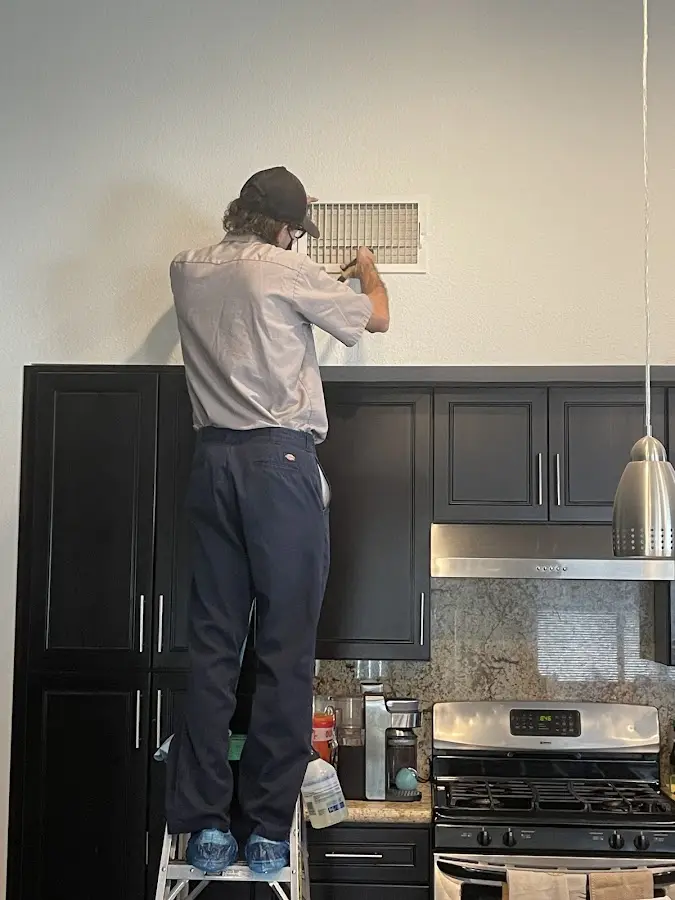 Technician inspecting an air vent during HVAC service in Ocean Springs